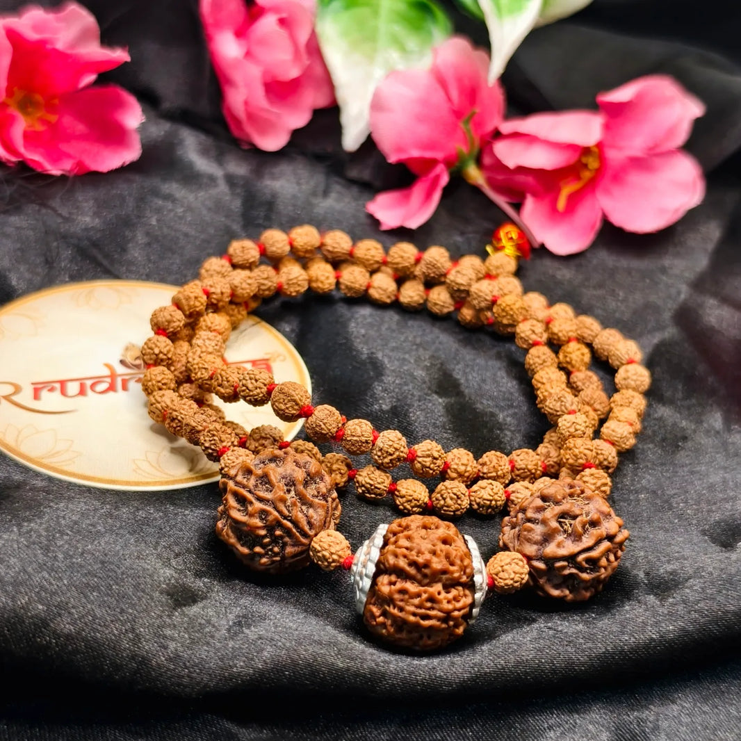 7 Mukhi beaded necklace on a dark fabric background with pink flowers