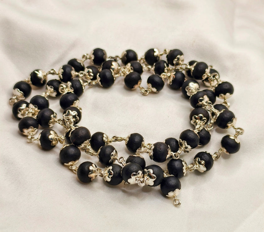 Ebony Wood beaded necklace with gold accents on a white fabric background. Premium Quality german silver karungali pendant 