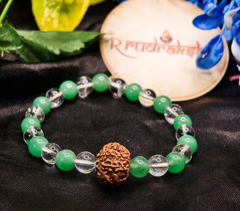 Green beaded bracelet with a brown knotted bead on a black fabric background