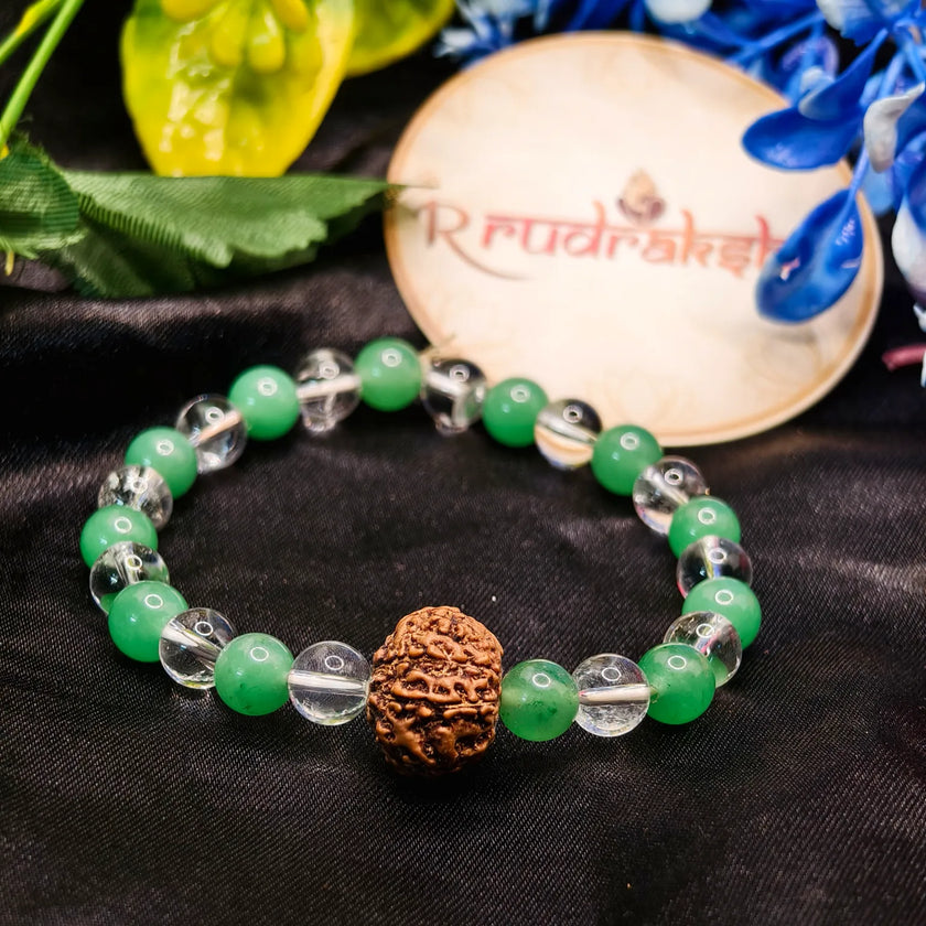 Green beaded bracelet with a brown knotted bead on a black fabric background