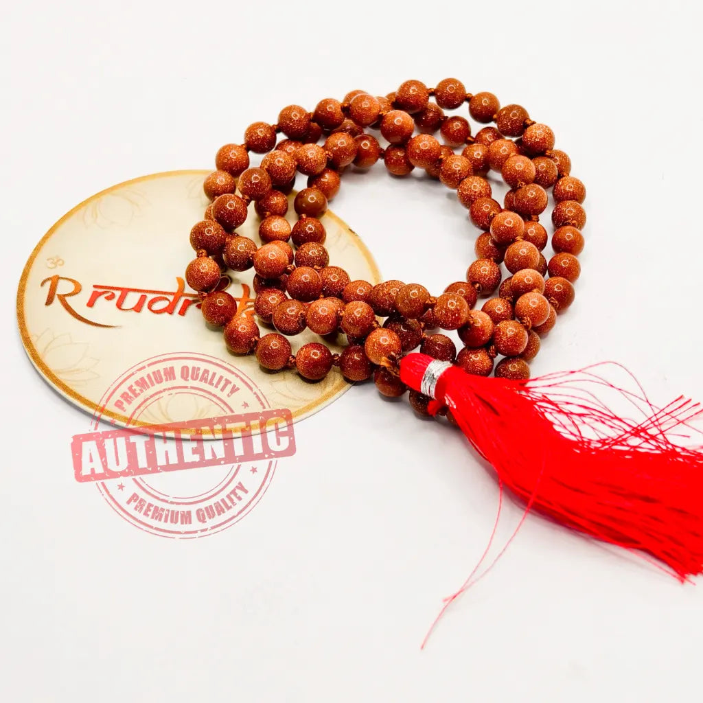 Sunstone beaded necklace/mala with a red tassel on a white background, featuring 'R Rudraksha' branding.