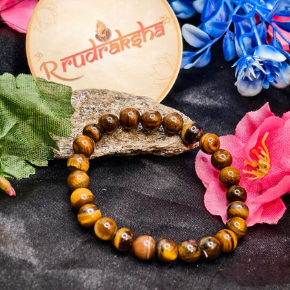 Tiger Eye Beaded bracelet Lab Certified , Premium Quality l, on a dark surface with flowers and a 'R Rudraksha' branded card